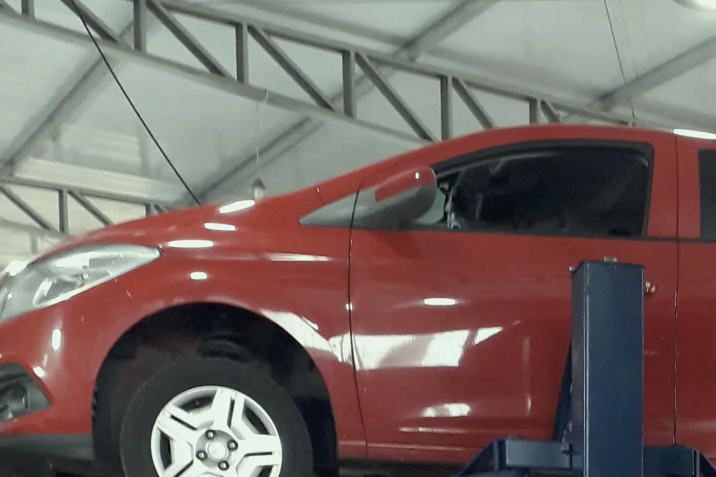 Carro vermelho erguido no elevador de duas colunas da oficina